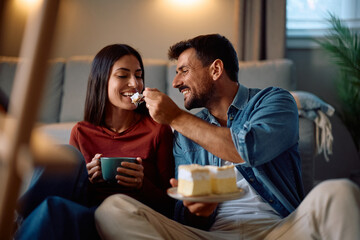 Happy couple sharing piece of cake at home.