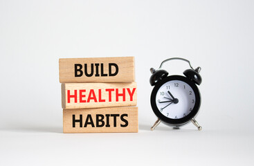 Healthy habits symbol. Concept word Build Healthy habits on wooden blocks with alarm clock....