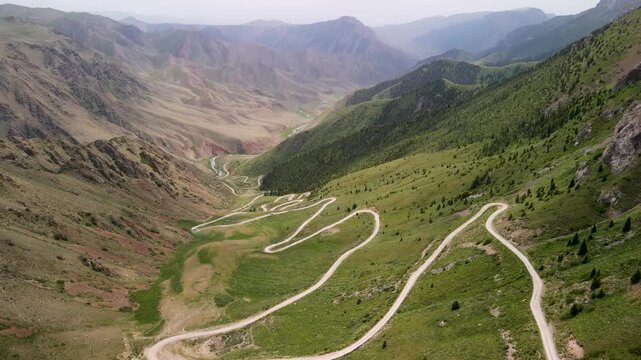 Aerial drone view of Teskey-Torpok Pass (38 Parrots), 3,138 m above sea level in Kyrgyzstan&rsquo;s Tien Shan mountains, with a winding dirt road running down the slope.