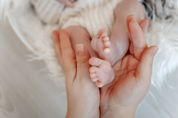 mother's hands holding baby's legs, baby's birth, mother's love and care, mother and baby