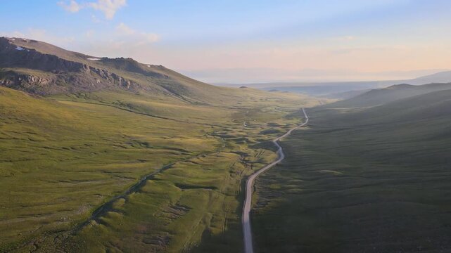 A winding dirt road cuts through the mountains, following a meandering river and leading to the northern shore of Lake Song-K&ouml;l. On this summer day, patches of snow remain on the slopes and peaks.