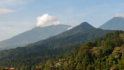 Fototapeta premium Mountains landscape. Panorama of beautiful countryside of Indonesia in sunny afternoon. landscape in tropical. Grassy field and rolling hills. rural scenery with blue sky and trees. Idyllic mountain.