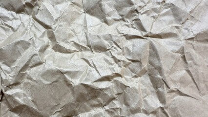 wrinkled beige kraft paper texture with natural light shadows ideal for packaging design or...