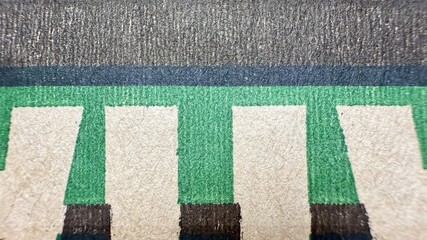 closeup of vintage textured paper print with bold green letter t on faded beige and black ink...