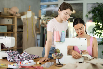 Woman dressmaker trains female assistant on job. Mentor comments on process of making clothes,...