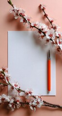 Blank white paper, coral pen, and delicate apricot blossoms arranged on a peach background; a minimalist, springtime scene suggesting writing or creativity