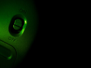A toggle switch is illuminated in green light, placed vertically with 
