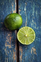 Two limes, one halved, rest on a rustic, blue-painted wooden surface showing age and texture.  The limes are bright green and appear juicy