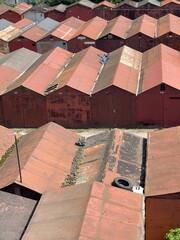 Rows of old, rusty garages with sloped roofs create a dense urban landscape. The weathered metal...