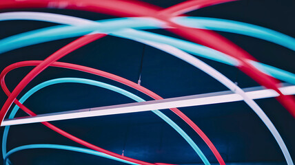 Dynamic motion of glowing red and cyan lines swirling around a modern linear light fixture, symbolizing data flow and energy.