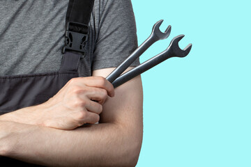 A young man, a car service worker with a wrench in his hand. Isolation.