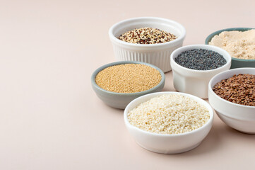 Assortment of superfoods, seeds, grains in bowls on light background. Amaranth, sesame, flaxseed, poppy, quinoa. Top view
