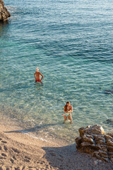 Family swimming at hidden Mediterranean beach with clear water