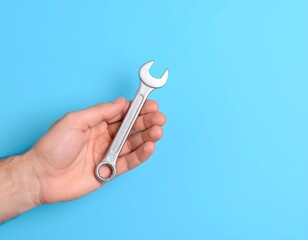 Hand holding a wrench against a vibrant blue background
