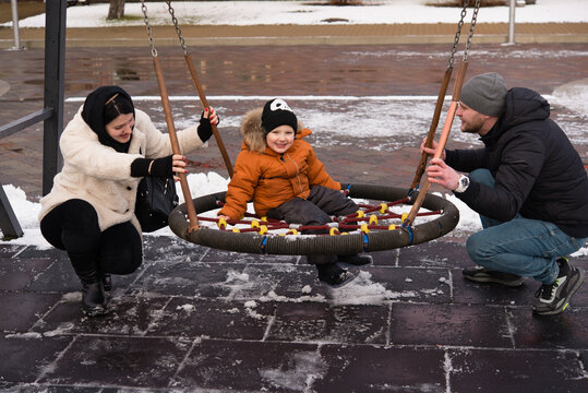 happy parents and son having fun on winter day on the playground on a snowy day - Powered by Adobe