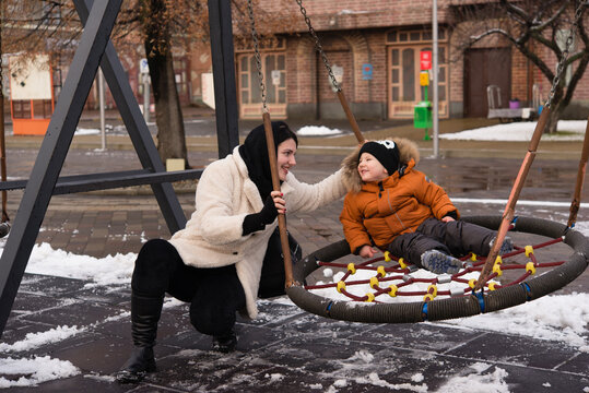 happy mother and son having fun on winter day on the playground on a snowy day