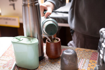 Detalle primer plano mano sirviendo agua en el mate  primer plano desenfoque selectivo