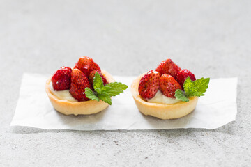 Two Vegan Round Strawberry tartlets. Light gray background. Close up
