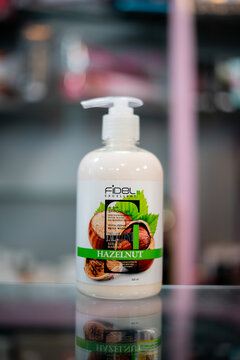 Amsterdam, Netherlands april 10, 2025. A Fidel brand hazelnut moisturizing body lotion in a tall white pump bottle, placed on a glass shelf. The label displays hazelnut imagery, suggesting rich