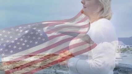 Senior woman standing on shore, tech flag overlay fading and waving, lifting chin scanning horizon - Powered by Adobe