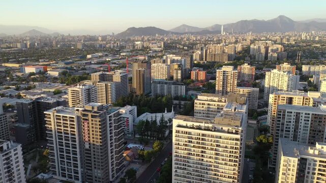 Atardecer dorado sobre los edificios de Macul, con sombras largas y cielo c&aacute;lido en Santiago de Chile