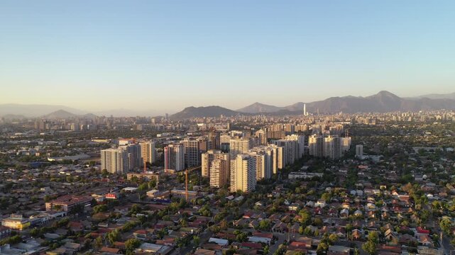 Atardecer dorado sobre los edificios de Macul, con sombras largas y cielo c&aacute;lido en Santiago de Chile
