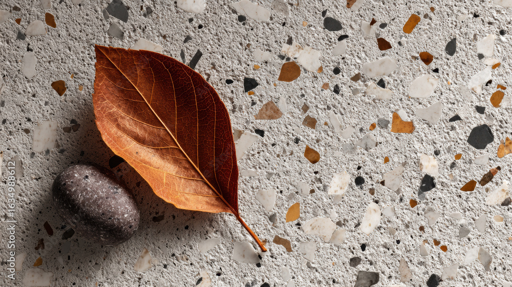 Poster minimal fall composition with terrazzo-style stone and dry leaf on a textured surface