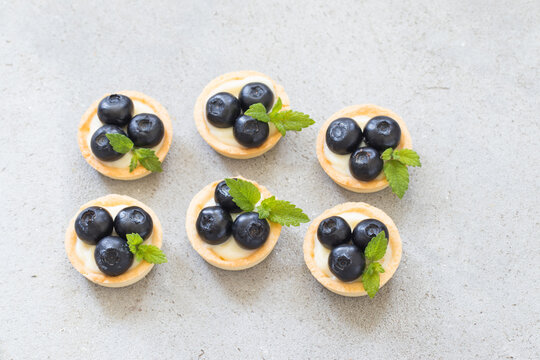 Mini round Blueberry tartlet. With custard. Light background. Top iew