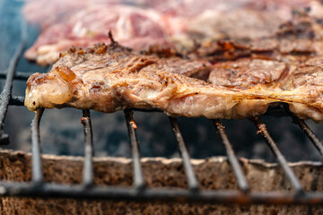 An extreme close-up of a thick, juicy beef steak cooking on the hot metal grates of a barbecue. Sizzling fat and beautiful grill marks highlight the delicious texture of the perfectly cooked meat.