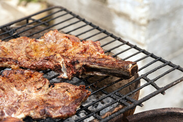 Two large, juicy beef steaks with beautiful char marks are cooked to perfection on a rustic barbecue grill. A close-up shot that evokes the delicious taste and aroma of grilled meat at a cookout.
