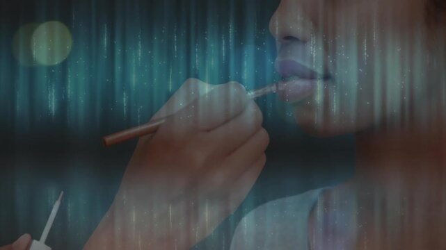 Makeup artist priming lips brushing rosy tint on model lips over turquoise lights for beauty look