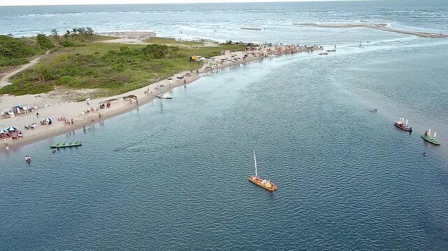 Breathtaking aerial view of Pontal de Maraca&iacute;pe beach in Porto de Galinhas, Pernambuco, Brazil. Tourists relax by the sea, and traditional jangada boats float on the calm blue water.