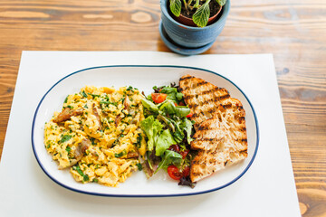 Warm brunch plate featuring scrambled eggs, toasted bread slices, and fresh salad served on a...