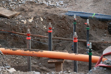Bunch of pipes are in the dirt, with some of them being orange