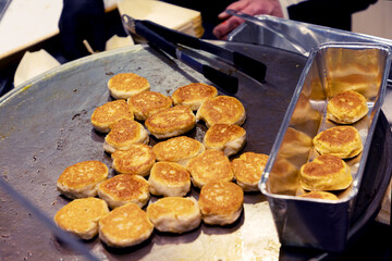 Freshly cooked golden pancakes on a griddle with a metal tray for serving delicious breakfast treats