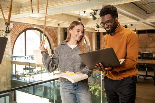 Two diverse coworkers standing and talking working on strategy in contemporary open office