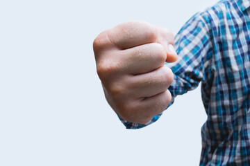 Fototapeta premium Close-up of a man in a shirt, doing a fist bump against on the light background. The concept of the fight.