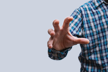 Close-up of a man in a shirt, making a hand grip with open palm on the light background.