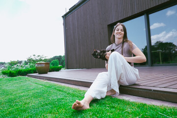 Woman near the home. Relax with cuty and funny cat in the terrace on sunny day
