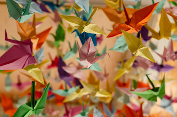 Hundreds of colorful origami cranes hanging on with strings from the ceiling. 