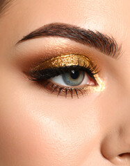 Obraz premium Close-up of an eye with glamorous golden makeup.