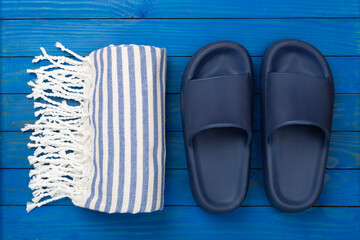 Beach towel with summer accessories on wooden background, top view