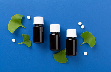 Ginkgo leaf with bottle of pills on color background, top view