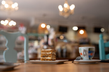Delicious slice of carrot cake and a cup of espresso served on a wooden table in a cozy cafe, with elegant lighting and a softly blurred background creating a warm and inviting atmosphere
