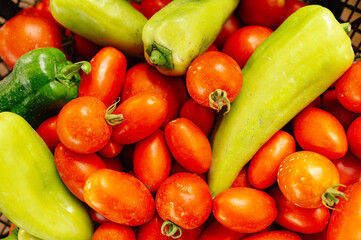 A vibrant mix of ripe red tomatoes and fresh green peppers, ideal for salads or various cooking uses