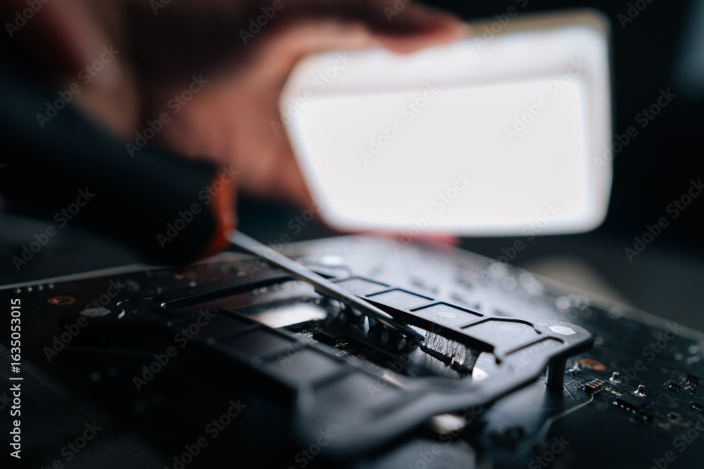 Poster close-up cropped shot of repairman using screwdriver to remove old thermal paste from cpu socket of 