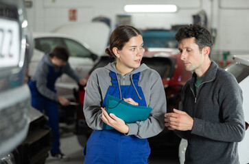 Auto repair shop manager discussing with male customer repair and insurance of his car at the auto...