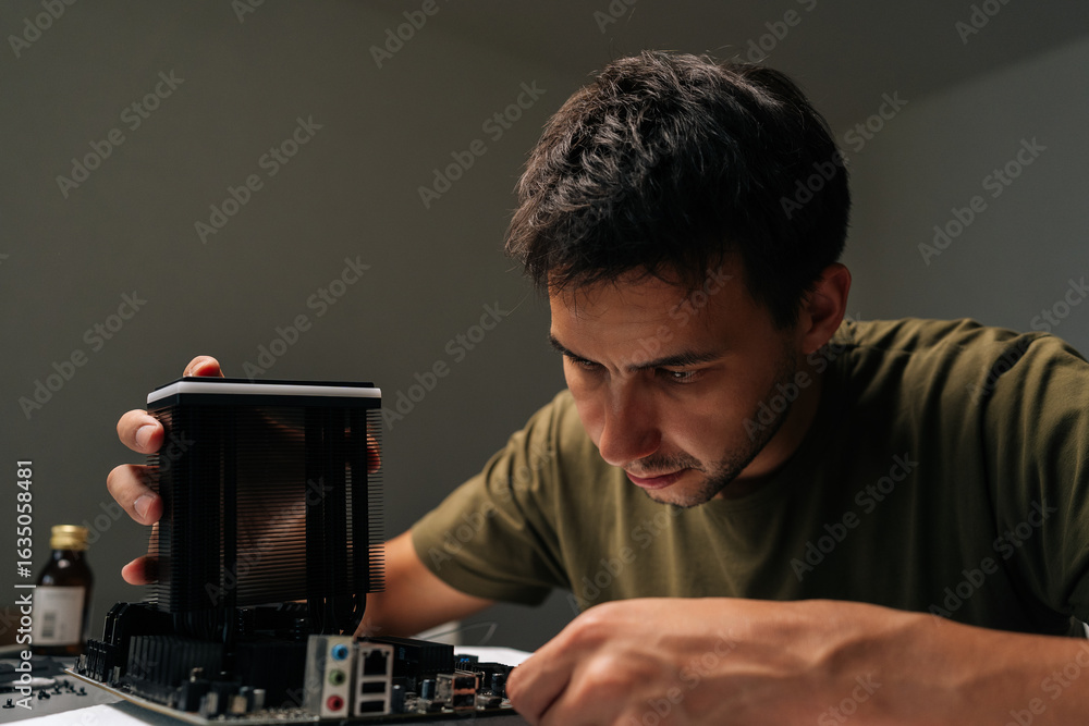 Poster close-up portrait of skilled computer technician male carefully installing cpu cooler onto motherboa