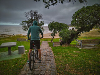 Man on mountain bike bicycle looking at coastal landscape, montevideo city, uruguay