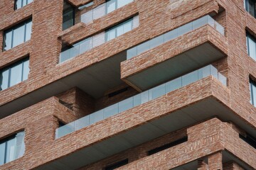 The contemporary brick structure, complete with stunning glass balconies, exemplifies an innovative architectural design that stands out in the bustling urban landscape.